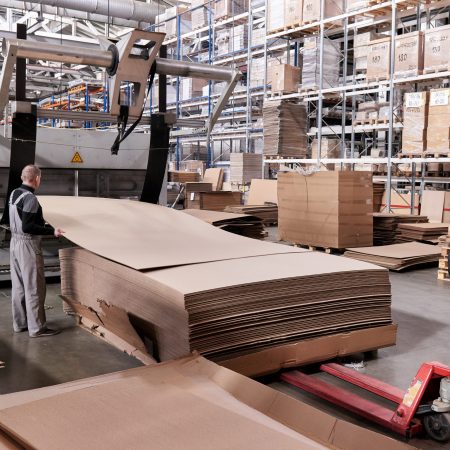 A worker processes furniture blanks on a complex technological machine at a factory. Industrial production of furniture