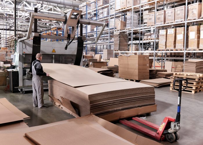 A worker processes furniture blanks on a complex technological machine at a factory. Industrial production of furniture