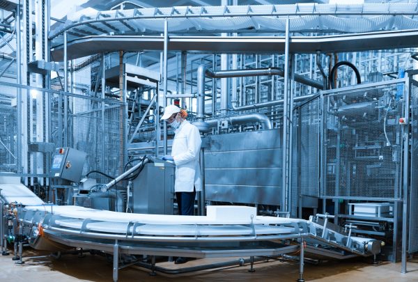 man in a white robe and a cap make an inspection of the production line technologist make set up of the production line while standing near digital screen at the department of dairy factory
